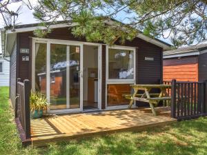 eine abgeschirmte Veranda eines winzigen Hauses mit einem Picknicktisch in der Unterkunft Harbour Cove - Uk47722 in Saint Merryn