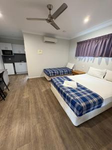 a bedroom with two beds and a ceiling fan at Reef Gardens Motel in Proserpine