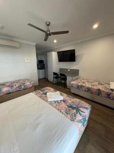 a hotel room with two beds and a table at Reef Gardens Motel in Proserpine