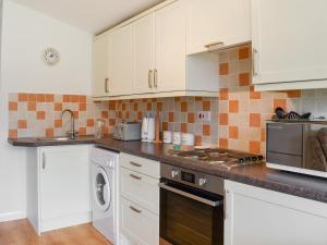 eine Küche mit weißen Schränken und einer Waschmaschine und einem Trockner in der Unterkunft Mother Ivy's Bay - Uk47553 in Saint Merryn