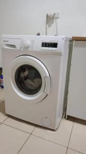 a white washing machine sitting on a kitchen floor at sea l in Jakarta