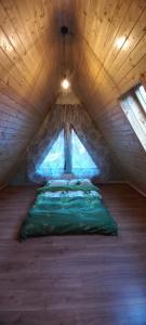 a room with a green bed in a attic at Cabana Doi Brazi A-FRAME in Dămuc