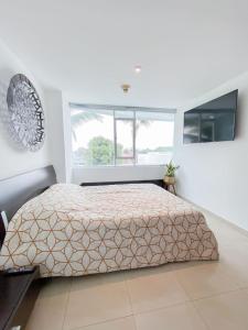 a white bedroom with a bed and a window at Perfecta Suite En Samborondon Plaza in Guayaquil
