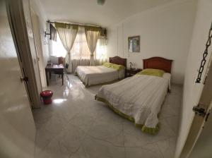 Un dormitorio con dos camas y un escritorio y una ventana. en Hotel Lord by Croma, en Cúcuta