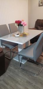 a white table and chairs with a vase of flowers on it at Room to stay in Lethbridge