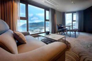 a living room with a couch and a large window at Ebenezer Hotel in Jeju