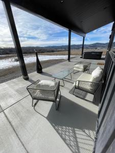 een terras met drie stoelen en een tafel en een glazen tafel bij Star Valley Barndominium Unit B in Thayne