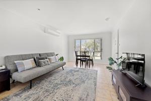 Una sala de estar con un sofá y un televisor. en Sandy Adventures - Pet Friendly - 1 Min to Beach, en Callala Beach