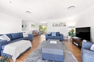 sala de estar con sofás azules y TV en Sandy Adventures - Pet Friendly - 1 Min to Beach, en Callala Beach