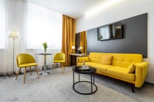 a living room with a yellow couch and chairs at Primma Hotel in Moldava nad Bodvou
