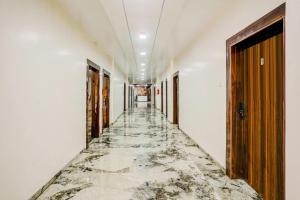 an empty corridor with marble floors and walls and doors at Super Collection O Ulhasnagar Birla Temple Formerly Hotel Yash Residency in Ulhasnagar