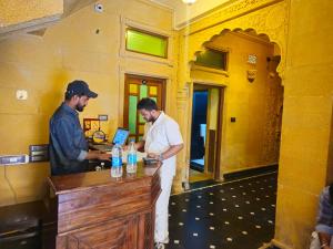 deux hommes debout à un comptoir dans un bar dans l'établissement Hotel The Vintage villa Jaisalmer, à Jaisalmer