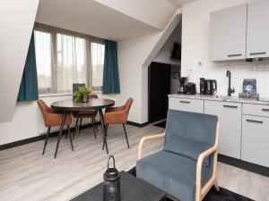 a living room with a table and a chair and a kitchen at Luxury apartment in Renesse with infrared sauna in Renesse