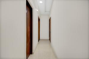 an empty corridor with white walls and wooden doors at Super Townhouse Pimple Nilakh Pune in Dāpuri