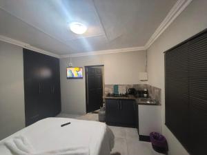 a bedroom with a white bed and a kitchen at The Good Samaritan 1 in eMalahleni