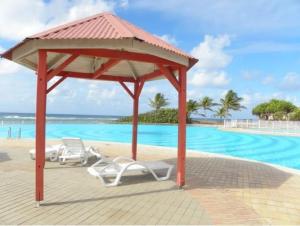 a gazebo with two white chairs and a swimming pool at Ti Mabouya Appartement Saint François in Saint-François