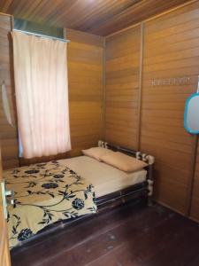 a bed in a wooden room with a window at Villa Kayu Danke in Ciguntur