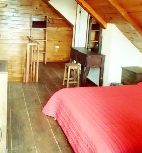 1 dormitorio con cama roja y pared de madera en Chalet Dominnycos, en San Cristóbal de Las Casas