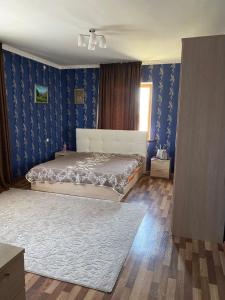 ein Schlafzimmer mit einem Bett und einer blauen Wand in der Unterkunft Гостевой дом с 7 комнатами in Schymkent