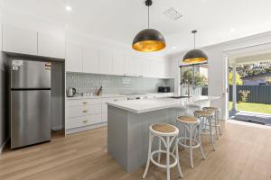 a kitchen with white cabinets and bar stools at Callala Chill Jervis Bay - Short Walk to Creek in Callala Bay