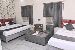 a hotel room with two beds and a chair at Sunaina Palace in Varanasi