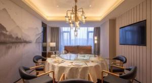 een eetkamer met een tafel, stoelen en een kroonluchter bij Zhejiang Cloud Mountain Deefly Hotel in Penshan