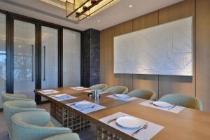 een vergaderzaal met een tafel en stoelen en een groot scherm bij Zhejiang Cloud Mountain Deefly Hotel in Penshan
