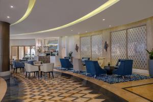 a restaurant with blue chairs and tables in a lobby at Al Habtoor Grand Resort, Autograph Collection in Dubai