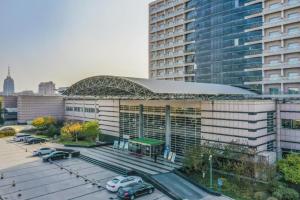 een groot gebouw met auto's geparkeerd op een parkeerplaats bij Jinjiang Hotel Qianan in Qian'an