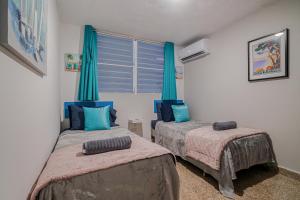 two beds in a room with blue curtains at Beach Side House Amazing For Family and Group by PH in Luquillo