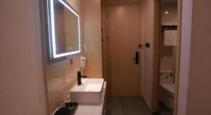 een badkamer met een witte wastafel en een spiegel bij Shell Hotel Chuzhou Economic Development Zone Internation Shangcheng in Chuzhou +110 foto's