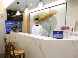 a man in a bow tie standing behind a counter at Green Tree Inn Express Beijing Xicheng District Dazhalan in Beijing