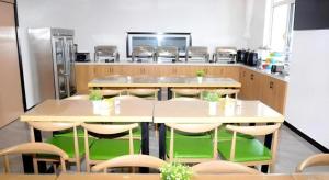 een keuken met tafels en stoelen en een koelkast bij Green Tree Inn Express Xingtai Guangzong Development Zone Xingqing Road in Guangzong