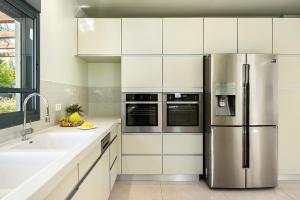 een keuken met witte kasten en een roestvrijstalen koelkast bij Tranquil Galilee Countryside Retreat by Sea N' Rent in Tefahot