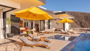 a house with a pool with chairs and umbrellas at Villa Damiana Boutique Hotel and Villa in El Pescadero