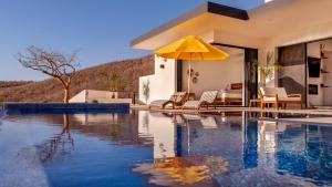 a house with a swimming pool with a yellow umbrella at Villa Damiana Boutique Hotel and Villa in El Pescadero