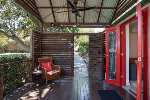 eine abgeschirmte Veranda mit einem Stuhl und einem Deckenventilator in der Unterkunft Petersons Wines Dairy Cottage in Pokolbin