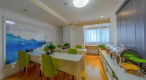 een grote kamer met tafels en groene stoelen bij Shell Hotel Huaibei Jinying Plaza Long Distance Bus Station in Huaibei