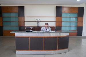 a man sitting at a counter in a lobby at Perfecta Suite En Samborondon Plaza in Guayaquil