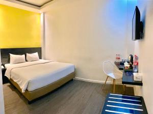 een hotelkamer met een bed en een stoel bij Rid's Hotel Palembang in Talang Kelapa +33 foto's