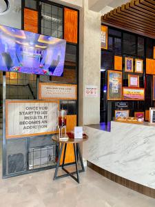 een balie in een gebouw met een tafel en een tv bij Rid's Hotel Palembang in Talang Kelapa