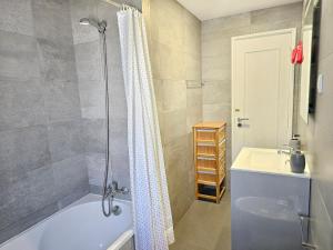 a bathroom with a shower curtain and a bath tub at Panorama Sun Figueira - 1er ligne Mer in Figueira da Foz +20 photos
