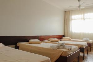 eine Gruppe von 4 Betten in einem Zimmer mit Fenster in der Unterkunft Cracco Park Hotel in Curitiba