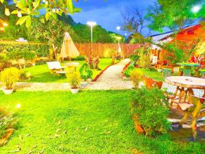 a garden with a table and a umbrella and a path at Suki Palm in Ban Bang Chak
