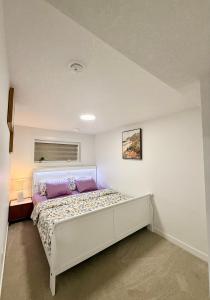 a bedroom with a large white bed with purple pillows at Cozy 2 Bedroom Suite Close to Amenities in Edmonton