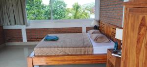 a bedroom with a bed and a brick wall at Amed Sari Beach Guesthouse in Amed