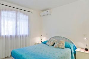 ポルト・チェルボにあるVilletta Il Mirtoの青いシーツのベッドと窓のある寝室