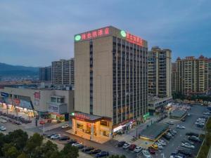 een hoog gebouw in een stad met een parkeerplaats bij Vienna Hotel Jiangxi Yongxin Shizheng Square in Yongxin