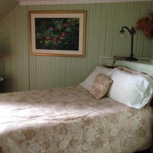 a bedroom with a bed with a picture on the wall at Auberge Les Blancs Moutons in Saint-Laurent-de-l'ile d'Orleans +43 photos