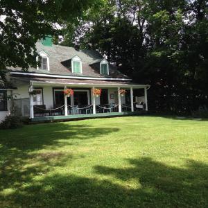 une maison avec une grande cour avec une pelouse dans l'établissement Auberge Les Blancs Moutons, à Saint-Laurent-de-l'ile d'Orleans